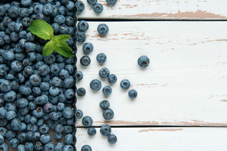 Baking mold with blueberry and mint leaves on the white Provence style wooden table. Flat lay. Copy space.の写真素材