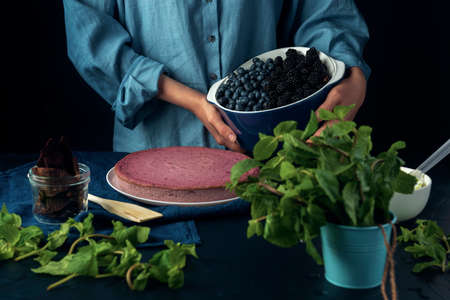 Woman holds bowl with blueberry and blackberry. Female ready for decoration cottage cheese casserole.の写真素材
