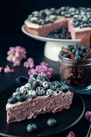 A piece of cottage cheese casserole with blackberry and blueberry. Cheese cake decorated with acacia flowers.の写真素材
