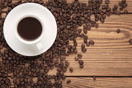 Cup of coffee with coffee beans on the wooden textured table.の写真素材