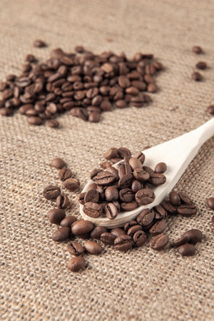 Wooden spoon with coffee beans on the burlap napkinの写真素材