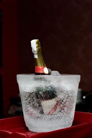 Champagne bottle encased in a bucket shaped block of ice on a red tray.
の写真素材