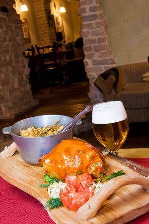 A closeup view of a variety of cooked food on a wooden tray and a glass of beer in a cozy setting.の写真素材