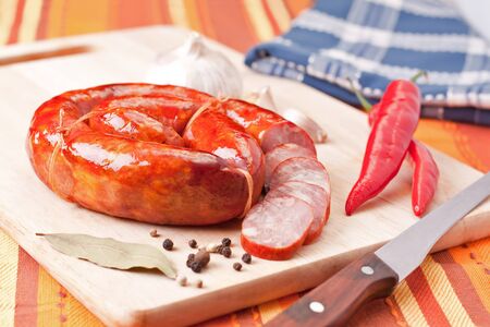 sausage, cayenne and knife on a wooden cutting board. の写真素材