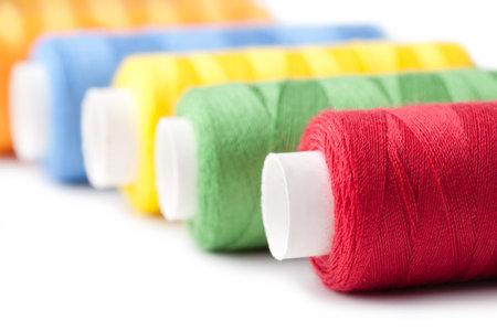 Pile of coloured bobbins of thread isolated on white
