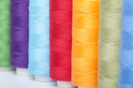 Pile of coloured bobbins of thread isolated on white