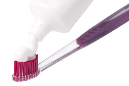Squeezing toothpaste onto toothbrush, on a white background