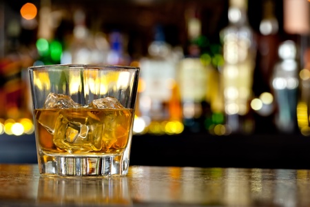 Glass of scotch whiskey and ice on the background of the barの写真素材