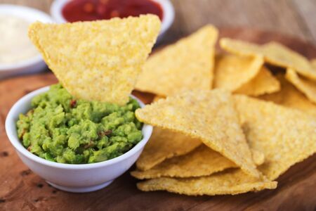 Corn chips nachos with sauce on a wooden table.の写真素材