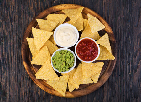 Corn chips nachos with sauce on a wooden table.