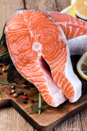 Slice of red fish salmon with lemon; rosemary on a wooden tableの写真素材