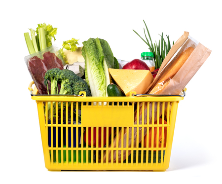 Plastic shopping basket with of grocery products isolated on whiteの写真素材