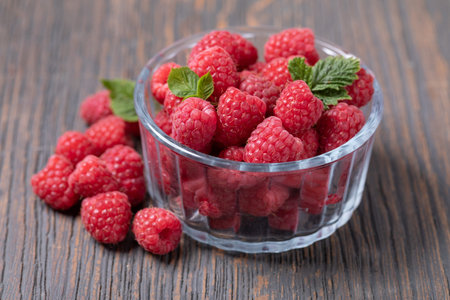 Raspberries in a bowl on a wooden background