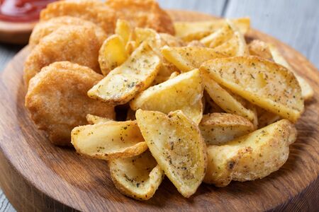 Tasty fried nuggets and potatoes on a tableの写真素材