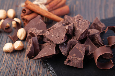 Pieces of natural dark chocolate on wooden table