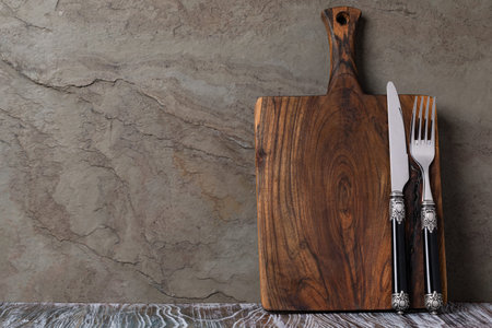 Rustic wooden cutting board on rusty stone background. empty copy space for text, design element