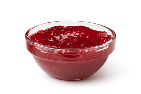 glass bowl of red berry jam isolated on white background