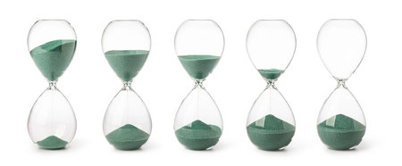 Collection of hourglasses with green sand on white background