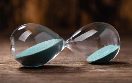 Selective focus of hourglass with green sand on wooden backgroundの写真素材