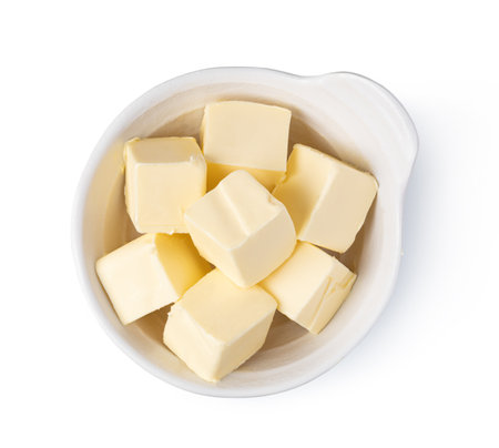 Small white ceramic bowl containing multiple butter cubes, isolated on a white backgroundの写真素材
