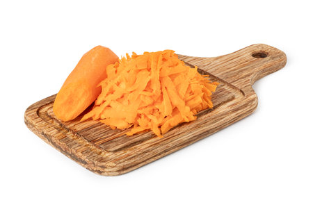 Grated carrots and a piece of carrot on a wooden cutting board, freshly prepared for cookingの写真素材