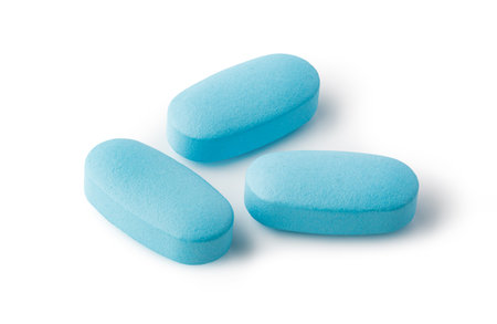 Three smooth, oval, light blue pills lie on a bright white background, representing healthcare, medicine, and treatmentの写真素材