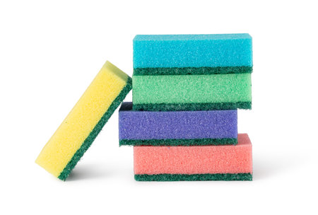 Multicolored sponges with abrasive green scouring pads arranged and leaning against a stack, creating a vibrant and practical cleaning sceneの写真素材