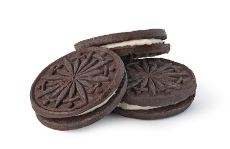 Chocolate cookies with cream filling showing a decorative radial pattern are lying on a white backgroundの写真素材