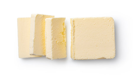 Creamy butter block and cut slices isolated on white, representing dairy products, cooking, and baking ingredientsの写真素材