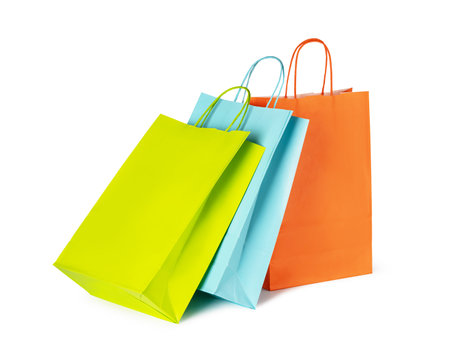 Vibrant yellow, orange, and blue shopping bags stand against a white background, symbolizing consumerism, retail, and the excitement of purchasingの写真素材