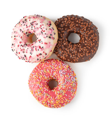 Delicious iced ring donuts with colorful sprinkles and cookie crumbs isolated on white background, creating a tempting display of sweet treatsの写真素材