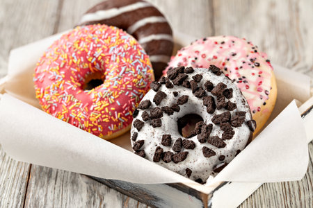 Colorful donuts with various toppings creating a tempting arrangement on a wooden tableの写真素材