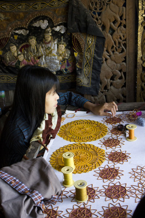 Burmese woman at work sewing beads  An artisan sews the canvas with beads  Sewing beads onto tapestry has an ancient history estimated to begin during the Paleolithic Age  のeditorial素材