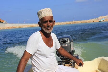 Sur, Oman, October 23, 2013: Omani fisherman at work. He is wearing the traditional omani hat, the kumma, used during unofficial time.のeditorial素材