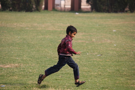 DELHI, INDIA: happy Indian child running in the grass, in the park of the Red Fort in Delhiのeditorial素材