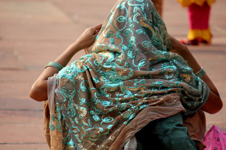 DELHI, INDIA: Indian girl from the backside, sit on the floor, with a beautiful turquoise green decorated veilのeditorial素材