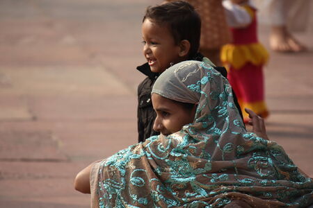 DELHI, INDIA - NOV 25: Indian girl from the backside, sit on the floor with her child, with a beautiful turquoise green decorated veilのeditorial素材