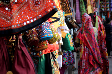PUSHKAR, INDIA: Street market in India, with colorful dressed and bags hung on the stand and Indian women in the backgroundのeditorial素材
