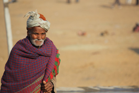 PUSHKAR, INDIA: Old Indian man with turban and white beard, covered with a blanket,  walking in Pushkarのeditorial素材