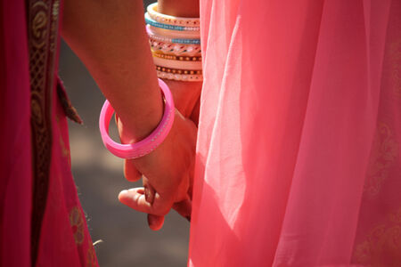 PUSHKAR, INDIA: Close up detail of the hands of two indian girl with pink veil, hand in hand walking in Pushkar, Indiaのeditorial素材