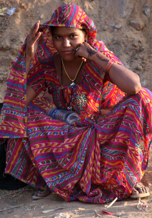 PUSHKAR, INDIA: Beautiful Indian young woman sit on the street at Pushkar Fair, with a colorful decorated red sareeのeditorial素材