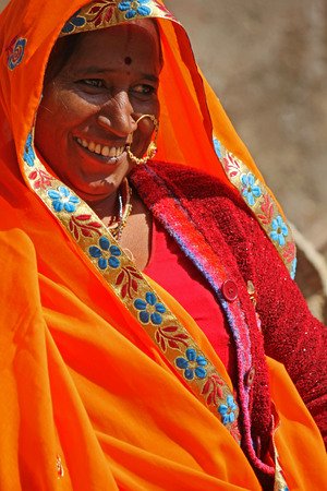 JAIPUR, INDIA - NOV 30: Indian woman with an orange vivid veil and the traditional indian tilak and nose ring, smiling on the street on 30 November 2012のeditorial素材