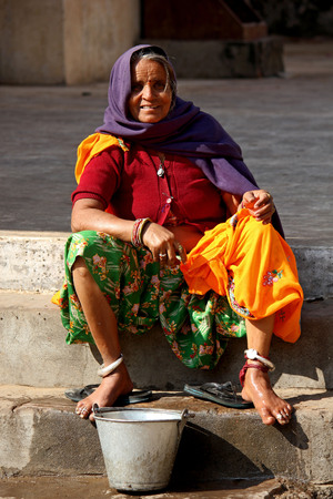 Old Indian woman sit outside a temple in Jaipur, barefoot.のeditorial素材