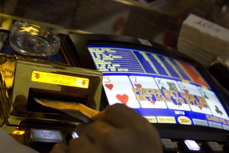 LAS VEGAS, USA - AUGUST 6 2013: Playing the slot machines in Las Vegas. Close up of a dollar to be inserted in the machineのeditorial素材