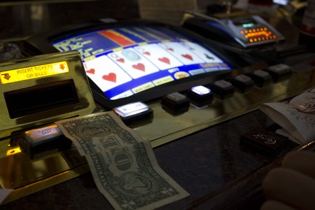 LAS VEGAS, USA - AUGUST 6 2013: Playing the slot machines in Las Vegas. Close up of a dollar to be inserted in the machineのeditorial素材
