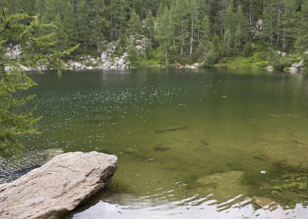 MADESIMO, ITALY - AUG 18 2014: Scenic view of Lago Azzurro (Blue Lake), a lake through trees in the high mountains in Italyのeditorial素材