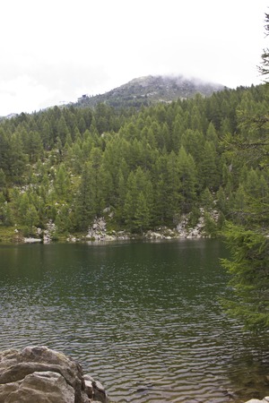 MADESIMO, ITALY - AUG 18 2014: Scenic view of Lago Azzurro (Blue Lake), a lake through trees in the high mountains in Italyのeditorial素材