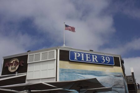 SAN FRANCISCO, USA - AUG 12 2013: Roof architectural detail of famous Pier 39 in San Francisco, with Hard Rock cafÃ¨ insigna and american flag  wavingのeditorial素材