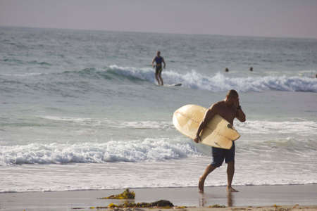SAN DIEGO, USA - AUGUST 20 2013: Surfer going out the water in Mission Bay in San Diegoのeditorial素材