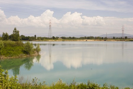 SIGNA, ITALY - MAY 9 2015:  Peaceful lake inside Renai Park in Signa, near Florence, with cloud reflected in the water and current poles in the backgroundのeditorial素材